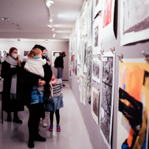 Prikaz Sa Otvorenja Izložbe, Detalj Yida S Radovima I Posjetitljima Koji Gledaju